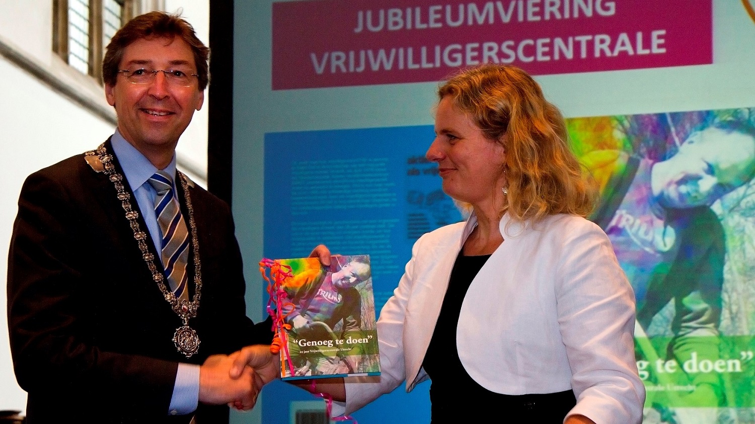 Annerieke van der Vegt, directeur Vrijwilligerscentrale Utrecht, reikt het eerste exemplaar van het jubileumboek uit aan burgemeester Aleid Wolfsen.